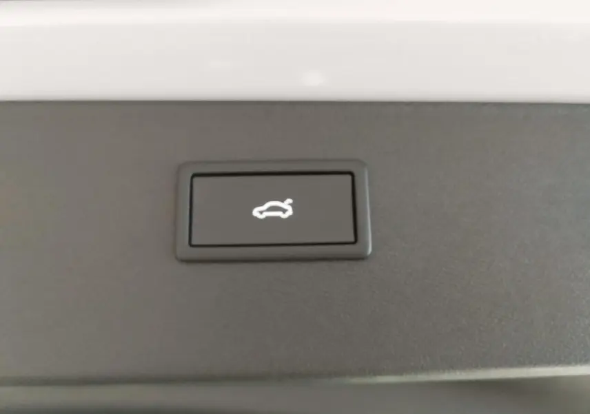 Bouton d'ouverture électrique du hayon sur fond noir, intérieur du coffre du CUPRA Formentor blanc Nevada White.