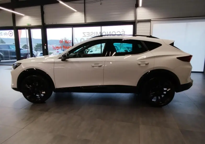 Vue latérale droite d'un CUPRA Formentor blanc Nevada avec jantes alliage noires dans un showroom.
