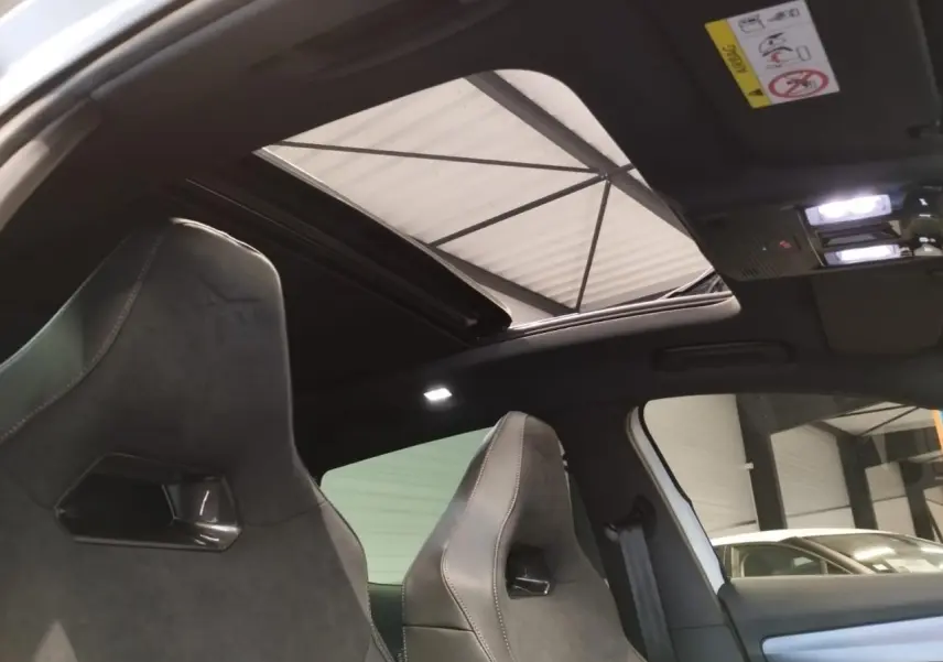 Vue intérieure des sièges baquets suédine noirs avec surpiqûres cuivrées et toit ouvrant panoramique du CUPRA Formentor blanc