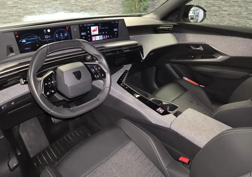 Intérieur du Peugeot 3008 2025 vu côté conducteur, volant compact cuir noir et tableau de bord numérique panoramique.