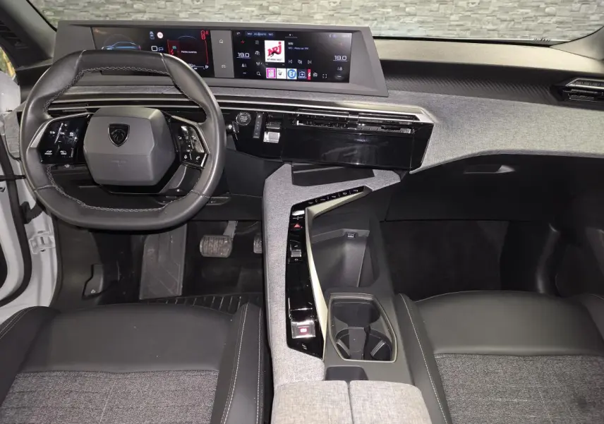 Intérieur Peugeot 3008 2025 vue du poste de conduite, volant compact cuir noir et double écran HD panoramique.