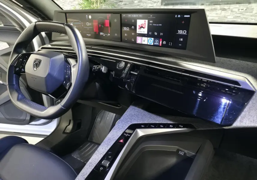 Vue intérieure du tableau de bord du Peugeot 3008 blanc 2025, avec volant compact cuir noir et double écran HD panoramique.