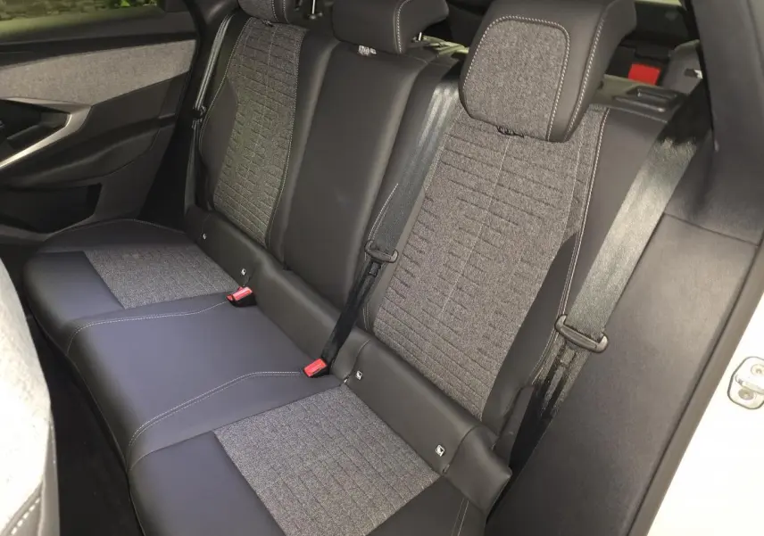 Vue intérieure de la banquette arrière du Peugeot 3008 blanc, avec sellerie tissu gris et cuir noir, ceintures de sécurité visibles.