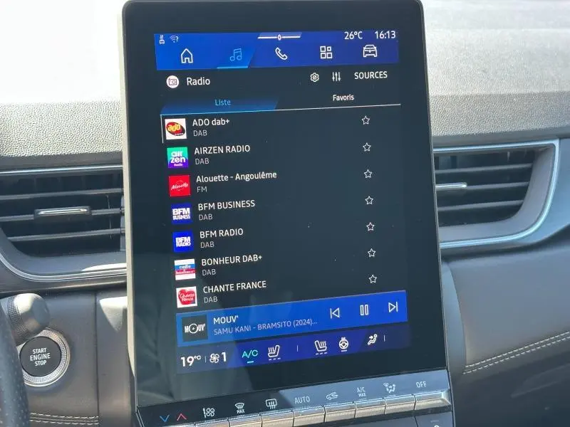 Gros plan sur l’écran tactile central du tableau de bord du Renault Symbioz rouge, affichant les stations radio numériques.