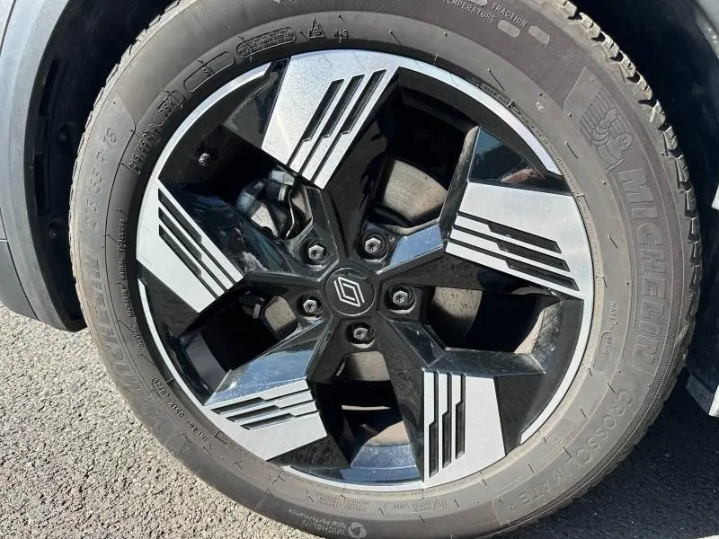 Gros plan sur la jante alu noire et argentée avec logo Renault, montée sur un pneu Michelin d’un Renault Symbioz rouge.