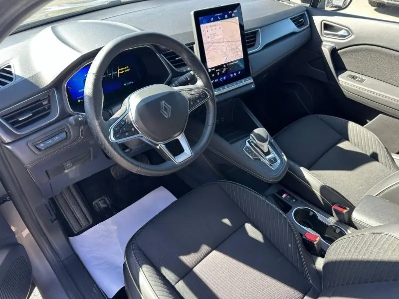 Vue intérieure côté conducteur de la Renault SYMBIOZ 2025 rouge, volant multifonction et écran tactile vertical.