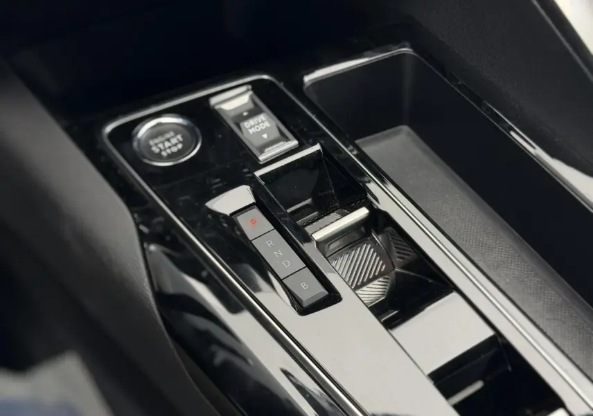 Vue rapprochée de la console centrale noire brillante du Peugeot 3008 Plug-in Hybrid avec sélecteur de mode de conduite et bouton start/stop.
