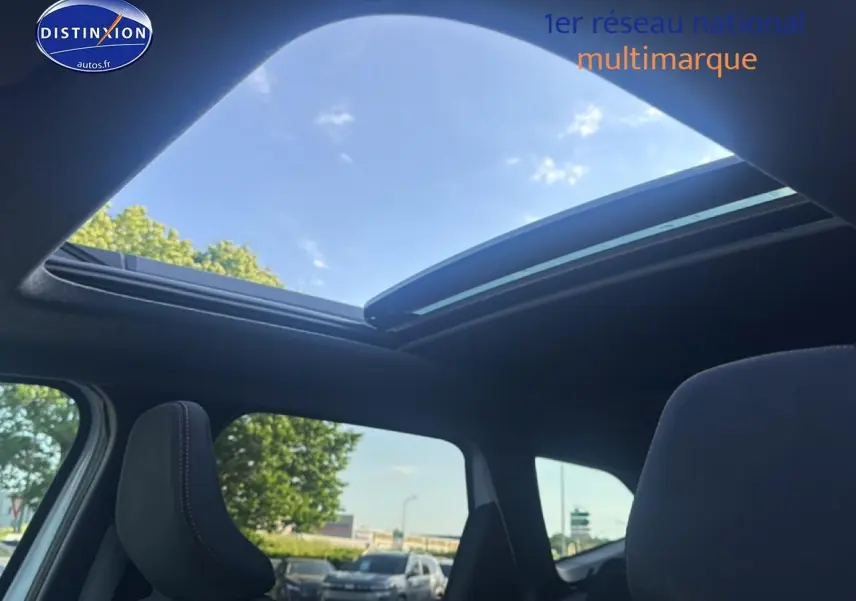 Vue intérieure du toit ouvrant panoramique en verre du Dacia Bigster blanc, avec ciel bleu visible à travers l'ouverture.
