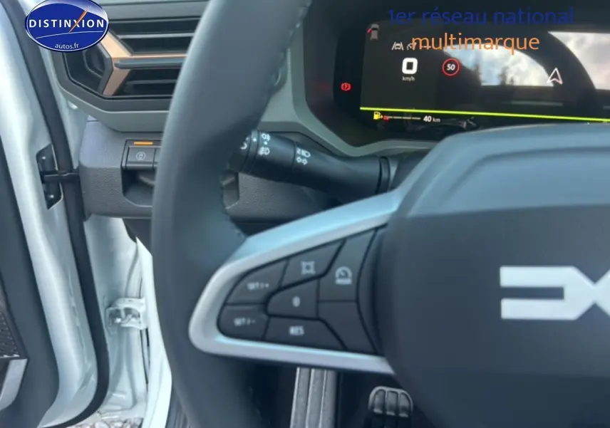 Gros plan sur le volant multifonction et le tableau de bord numérique du Dacia Bigster blanc, côté conducteur ouvert.