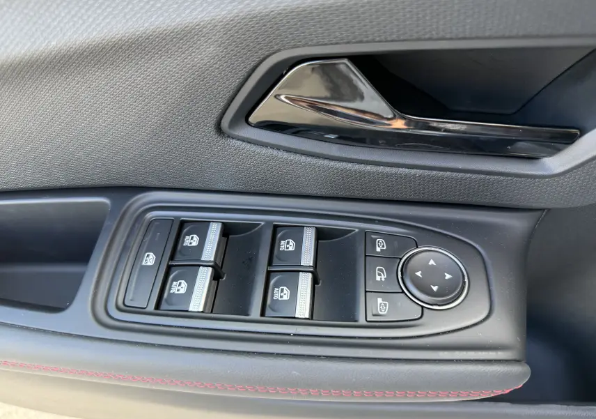 Gros plan sur la commande des vitres et rétroviseurs côté conducteur de la Renault Clio VI TCe 115 Techno gris Rafale.