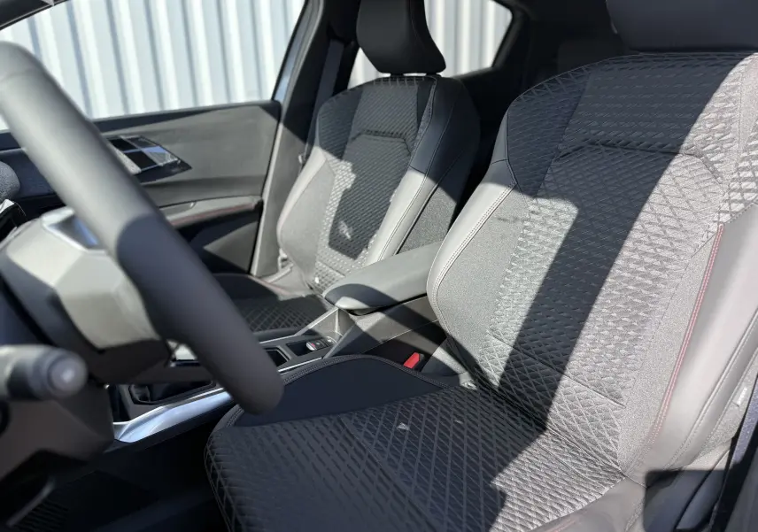 Vue intérieure rapprochée des sièges avant en tissu et cuir noir avec surpiqûres rouges de la Renault Clio VI TCe 115 Techno.