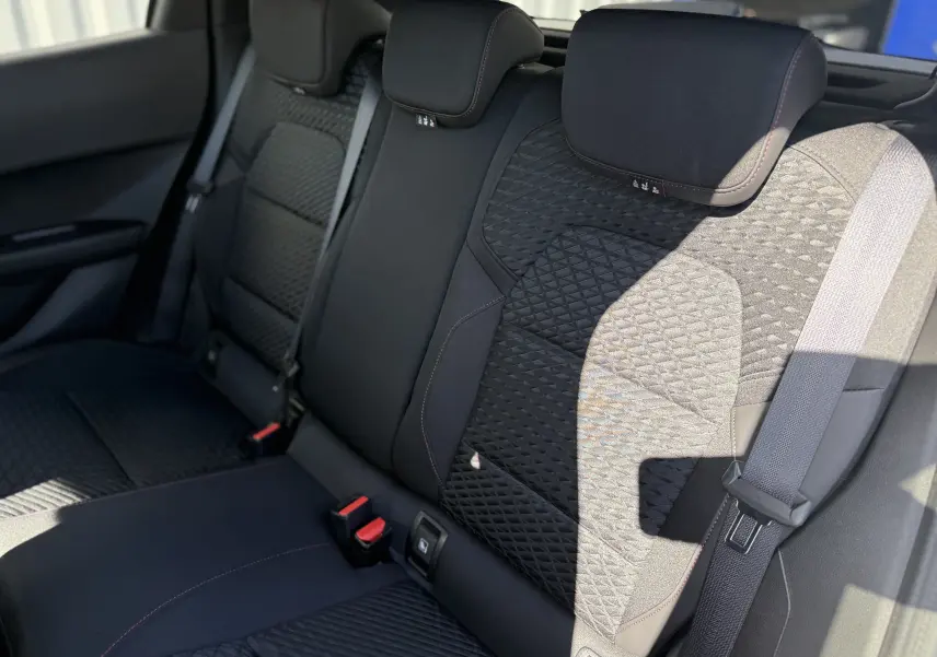 Vue rapprochée des sièges arrière noirs avec surpiqûres rouges de la Renault Clio VI TCe 115 Techno 2026.