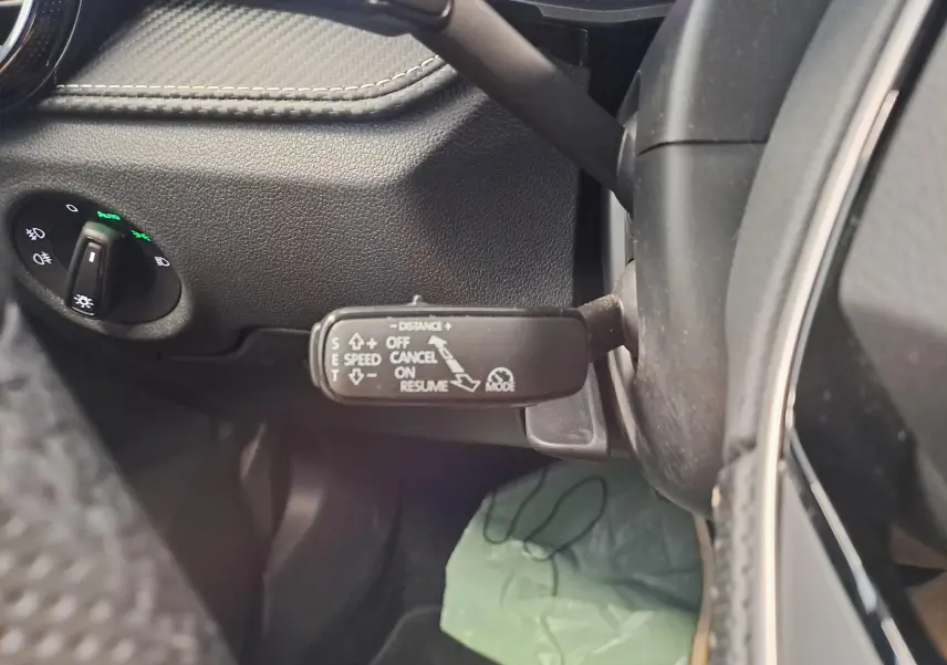 Vue rapprochée du commodo de régulateur de vitesse adaptatif sur le côté gauche du volant d'une Skoda Fabia noire.