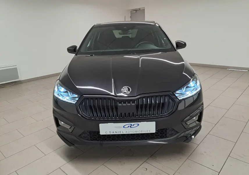 Vue frontale d'une Skoda Fabia 1.5 TSI 150 DSG7 Monte-Carlo en Noir Magic Nacré avec phares LED allumés.