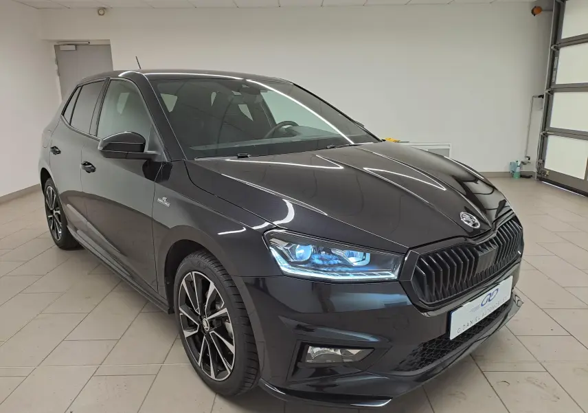 Vue 3/4 avant d'une Skoda Fabia 1.5 TSI 150 DSG7 Monte-Carlo noire Magic Nacré avec phares LED allumés en intérieur.