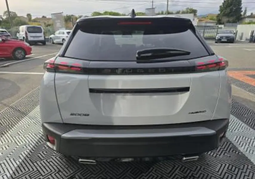 Vue arrière d'un Peugeot 2008 blanc Okenite avec toit noir, feux LED 3 griffes et double sortie d'échappement chromée.