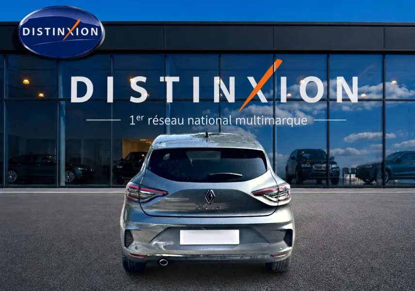 Vue arrière d'une Renault Clio V gris schiste garée devant une vitrine avec logo Distinxion.