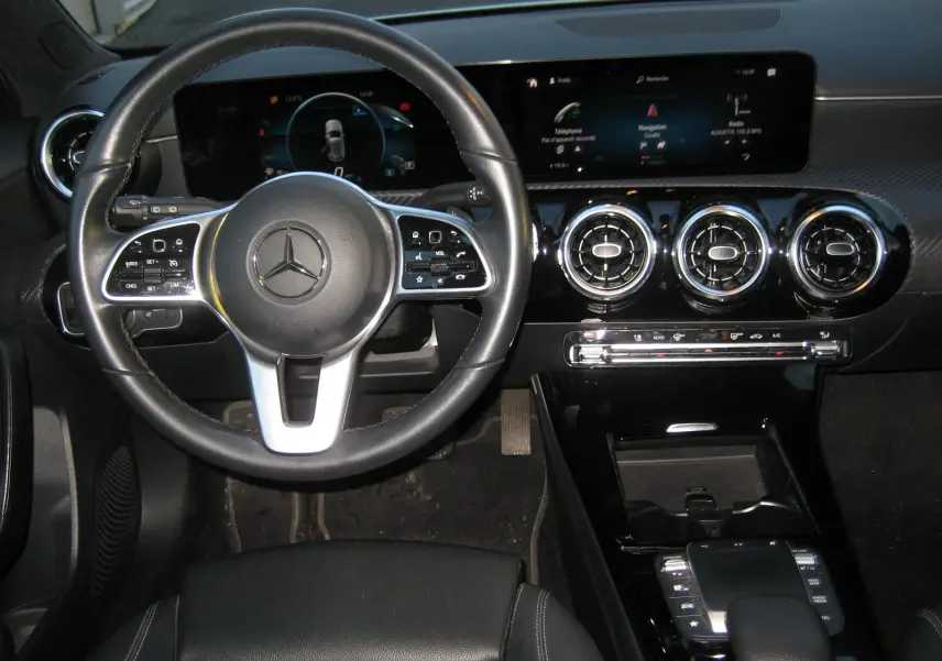 Vue intérieure centrée sur le volant cuir noir et le tableau de bord numérique de la Mercedes Classe A 180d Business Line.