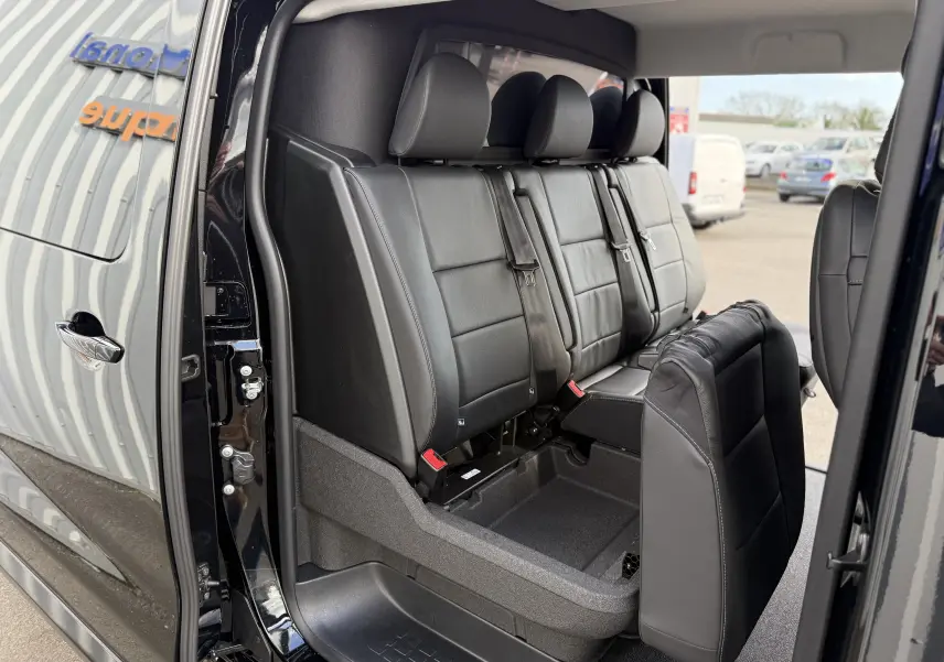 Vue latérale intérieure du Citroën Jumpy noir Perla montrant la banquette arrière en cuir avec siège rabattable.