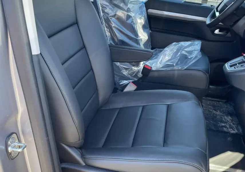 Vue intérieure côté conducteur du Citroën Jumpy Cabine Approfondie 2026, siège en cuir noir avec commandes électriques visibles.