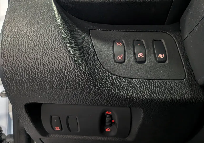 Gros plan sur les commandes de réglage et assistances du tableau de bord noir du Renault Kangoo Express Blanc Minéral 2020.