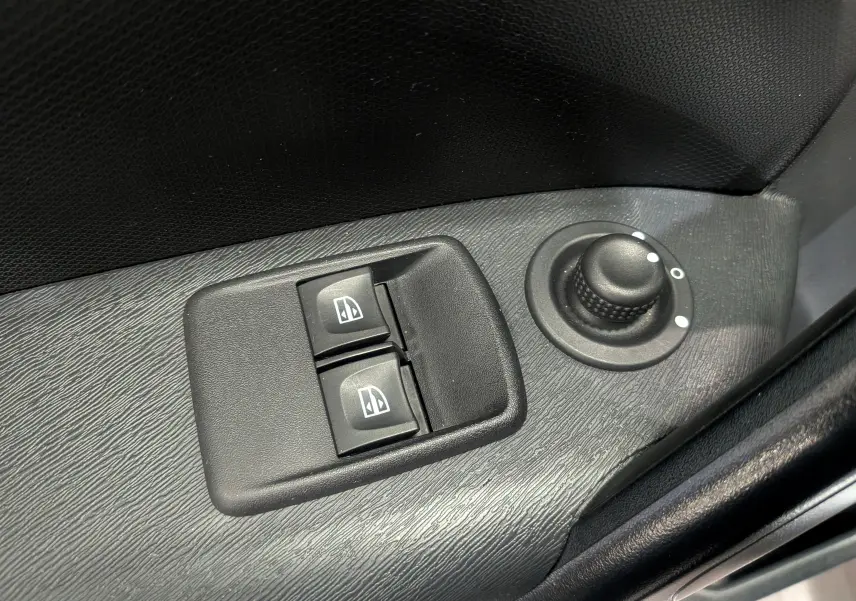 Gros plan sur les commandes des vitres électriques et le réglage des rétroviseurs côté conducteur du Renault Kangoo Express blanc.