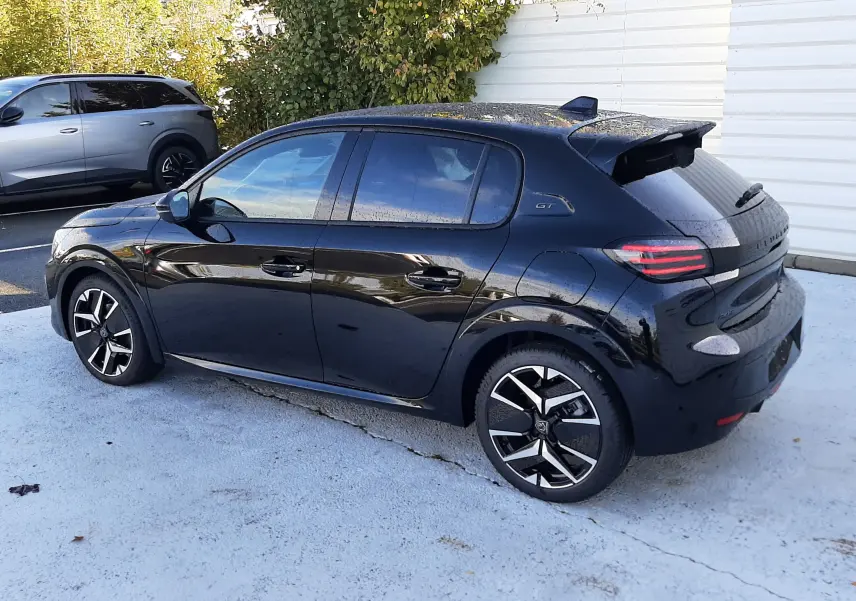 Peugeot 208 Hybrid 145ch GT noire perla vue 3/4 arrière côté gauche, avec jantes biton et toit spoiler.