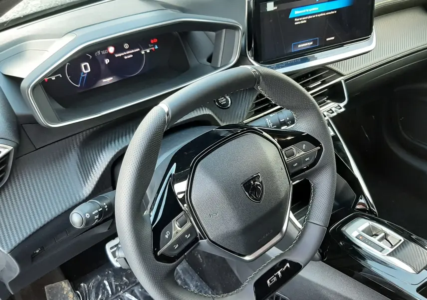 Vue intérieure du poste de conduite de la Peugeot 208 Hybrid 145ch GT, volant compact GT et écran tactile central.