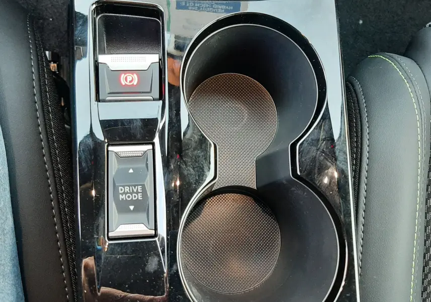 Vue plongeante sur la console centrale noire perla de la Peugeot 208 Hybrid 145ch GT avec boutons Drive Mode et frein électrique.