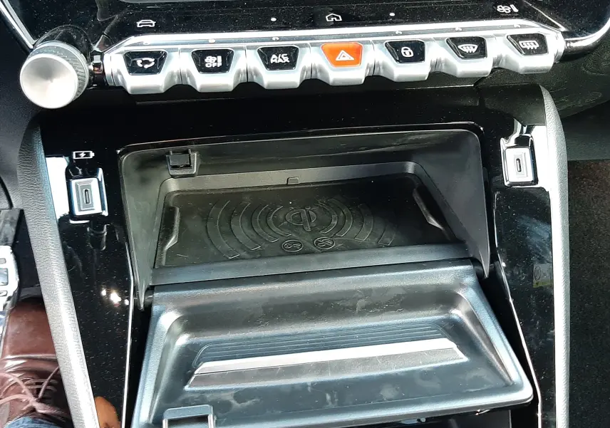 Vue rapprochée de la console centrale noire perla du Peugeot 208 Hybrid 145CH GT avec commandes et rangement ouvert.