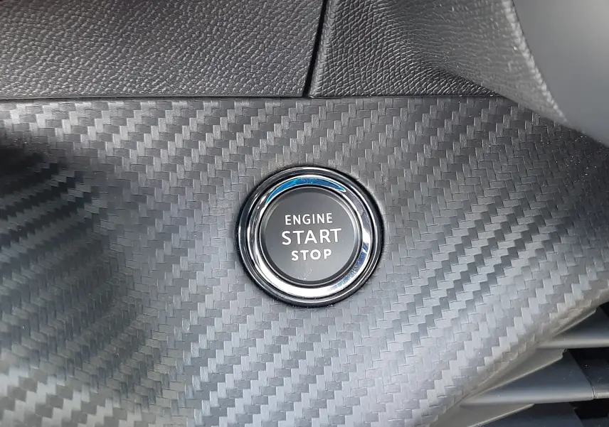 Bouton start/stop moteur sur tableau de bord en finition carbone du Peugeot 208 Hybrid 145ch GT 2026.