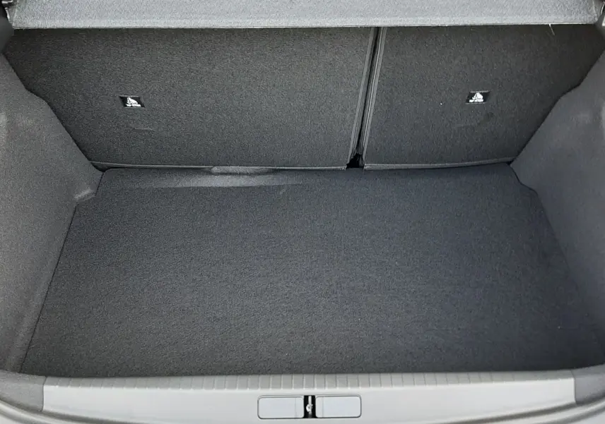 Vue 3/4 arrière droite d'une Peugeot 208 Hybrid 145ch GT noire perla avec gouttes d'eau sur la carrosserie.
