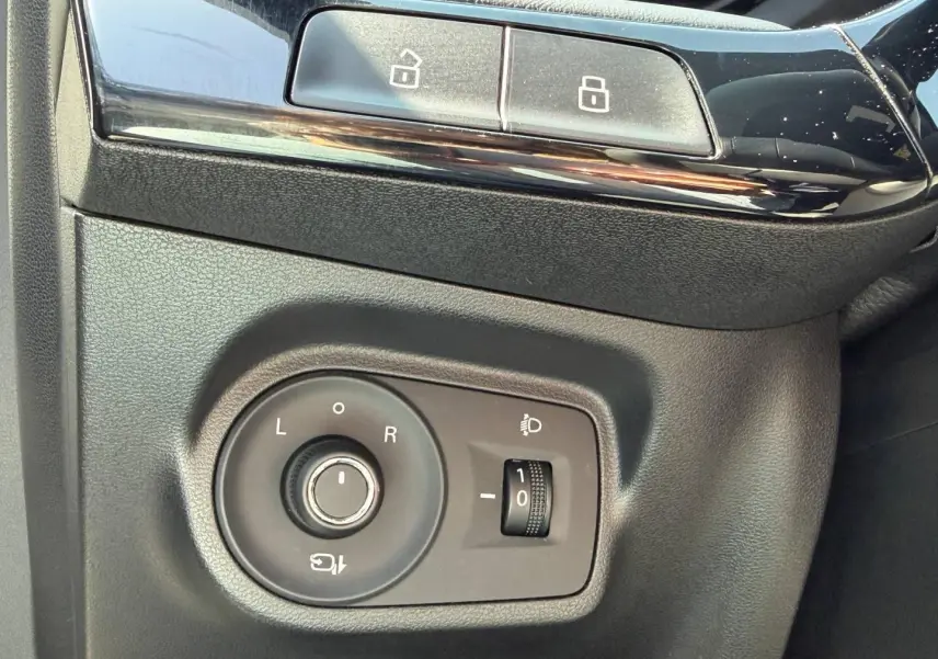 Détail des commandes de réglage des rétroviseurs et des phares sur le côté gauche intérieur d'un MG3 blanc 2025.