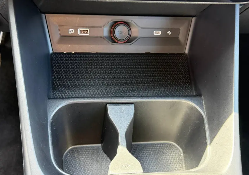 Gros plan sur la console centrale noire du MG3 1.5 Hybrid+ 2025, avec prise 12V et ports USB visibles.
