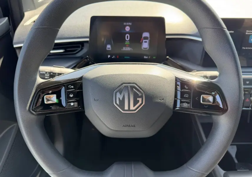 Vue rapprochée du volant noir de la MG3 1.5 Hybrid+ 195ch Comfort avec logo MG et écran numérique en arrière-plan.