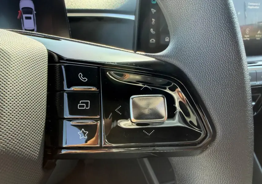 Gros plan sur les commandes noires au volant du MG3 1.5 Hybrid+ blanc, avec touches multifonctions visibles.