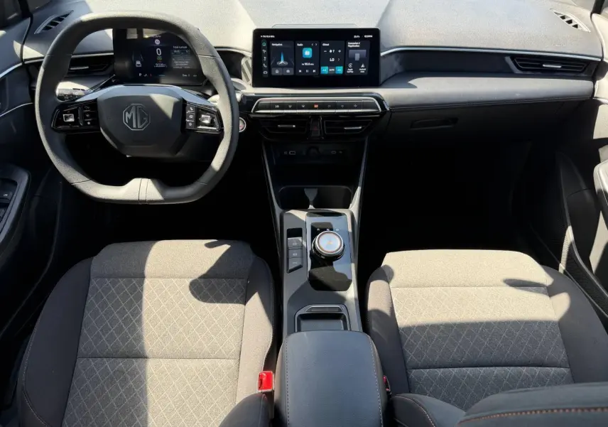 Vue intérieure avant du MG3 1.5 Hybrid+ 2025, montrant tableau de bord moderne avec écran tactile et sièges tissu gris.