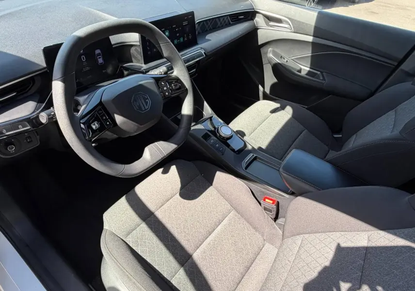 Vue intérieure côté conducteur du MG3 1.5 Hybrid+ 2025, sièges tissu gris et tableau de bord moderne avec écran tactile.