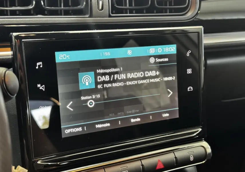 Écran tactile central de 7 pouces affichant la radio DAB dans l’habitacle noir de la Citroën C3 blanche, vue rapprochée.