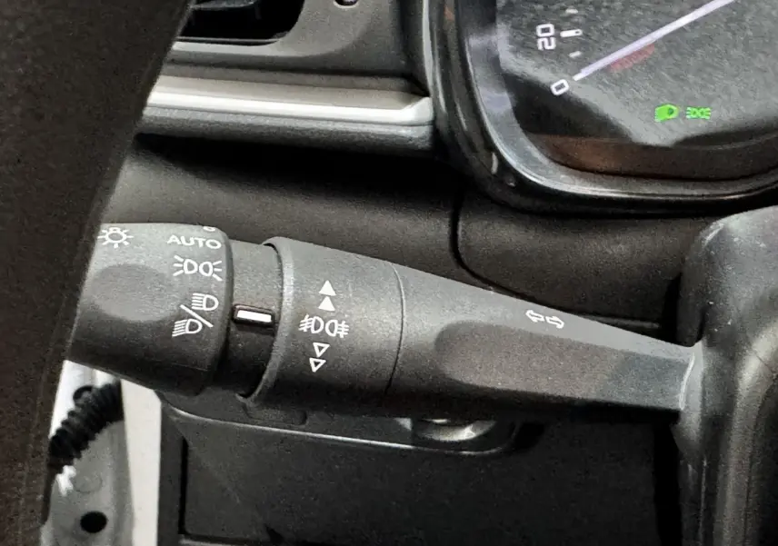 Gros plan sur la manette de clignotants noire du tableau de bord d'une Citroën C3 blanche, version 2024.