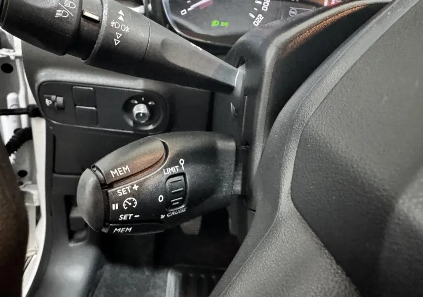 Gros plan sur la commande de régulateur de vitesse à gauche du volant dans une Citroën C3 blanche 2024.