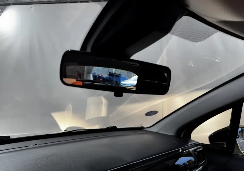 Vue intérieure du tableau de bord noir et du rétroviseur central d'une Citroën C3 blanche 2024.