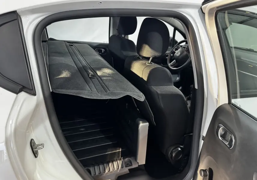Vue intérieure côté droit d'une Citroën C3 blanche 2024 avec siège arrière rabattable et plancher de coffre visible.