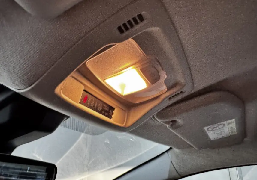 Plafonnier intérieur allumé de la Citroën C3 blanche 2024, vue en gros plan sous le toit côté conducteur.
