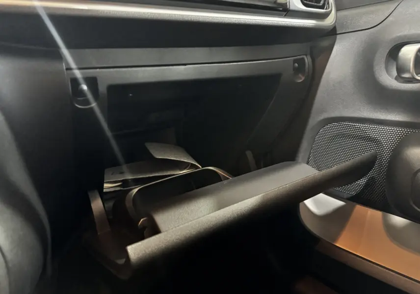 Vue intérieure rapprochée de la boîte à gants ouverte côté passager de la Citroën C3 blanche, montrant des documents à l’intérieur.