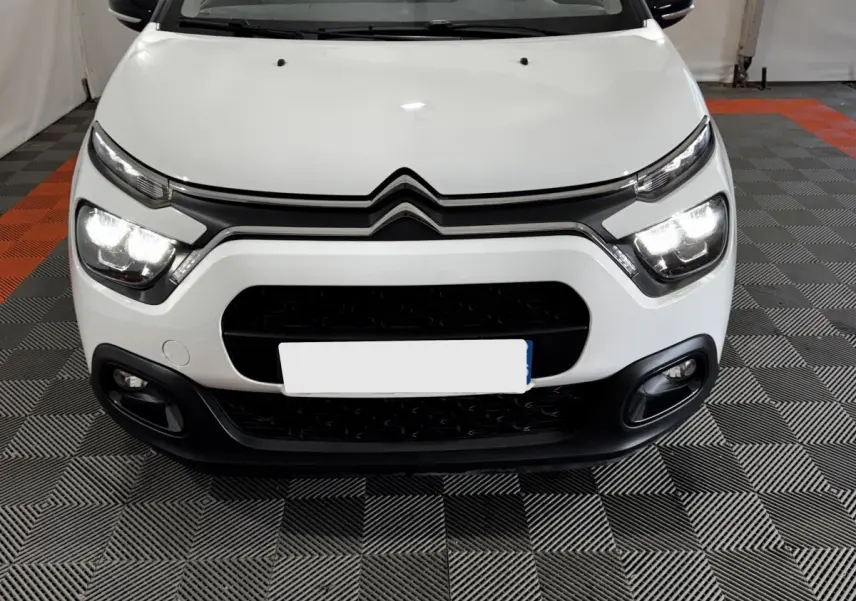 Vue frontale d'une Citroën C3 blanche 2024 avec phares LED allumés et calandre noire distinctive.