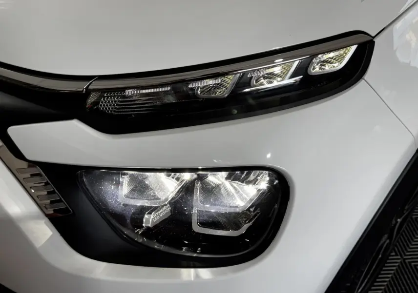 Gros plan sur le phare avant droit blanc de la Citroën C3 2024 avec éclairage LED distinctif et détails noirs.