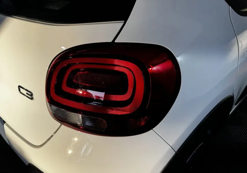 Gros plan sur le feu arrière droit rouge d'une Citroën C3 blanche, avec logo C3 visible sur la malle arrière.