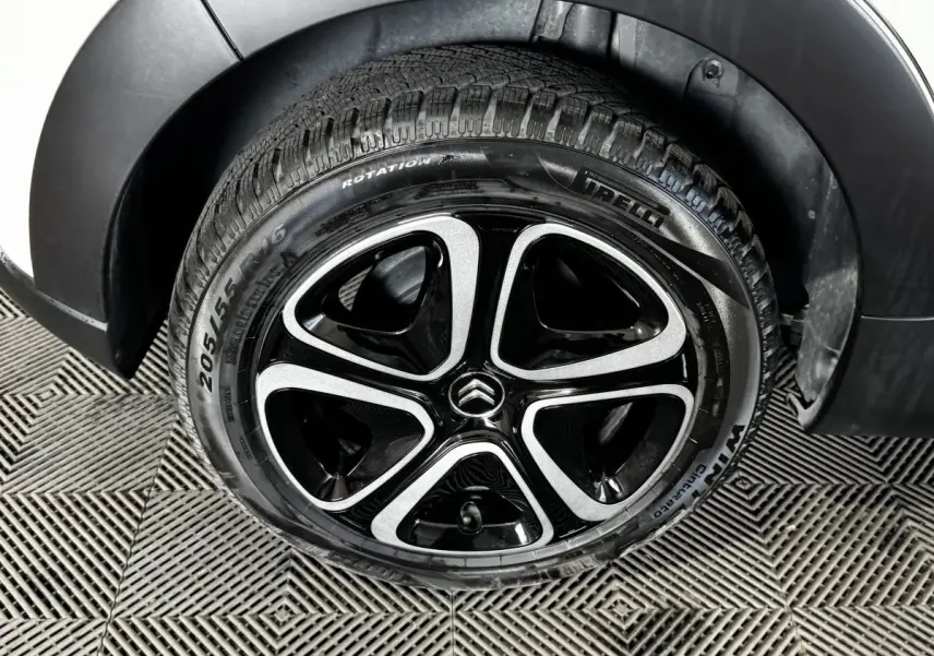Gros plan sur la roue avant droite d'une Citroën C3 blanche, jante alliage noire et argent avec logo Citroën central.