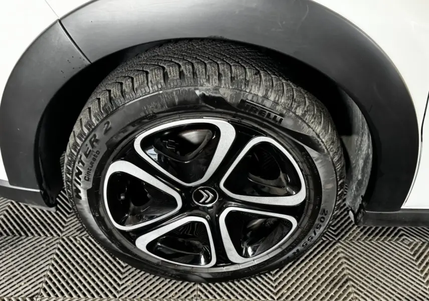 Gros plan sur la roue avant droite d'une Citroën C3 blanche avec jante noire et argentée au design moderne.